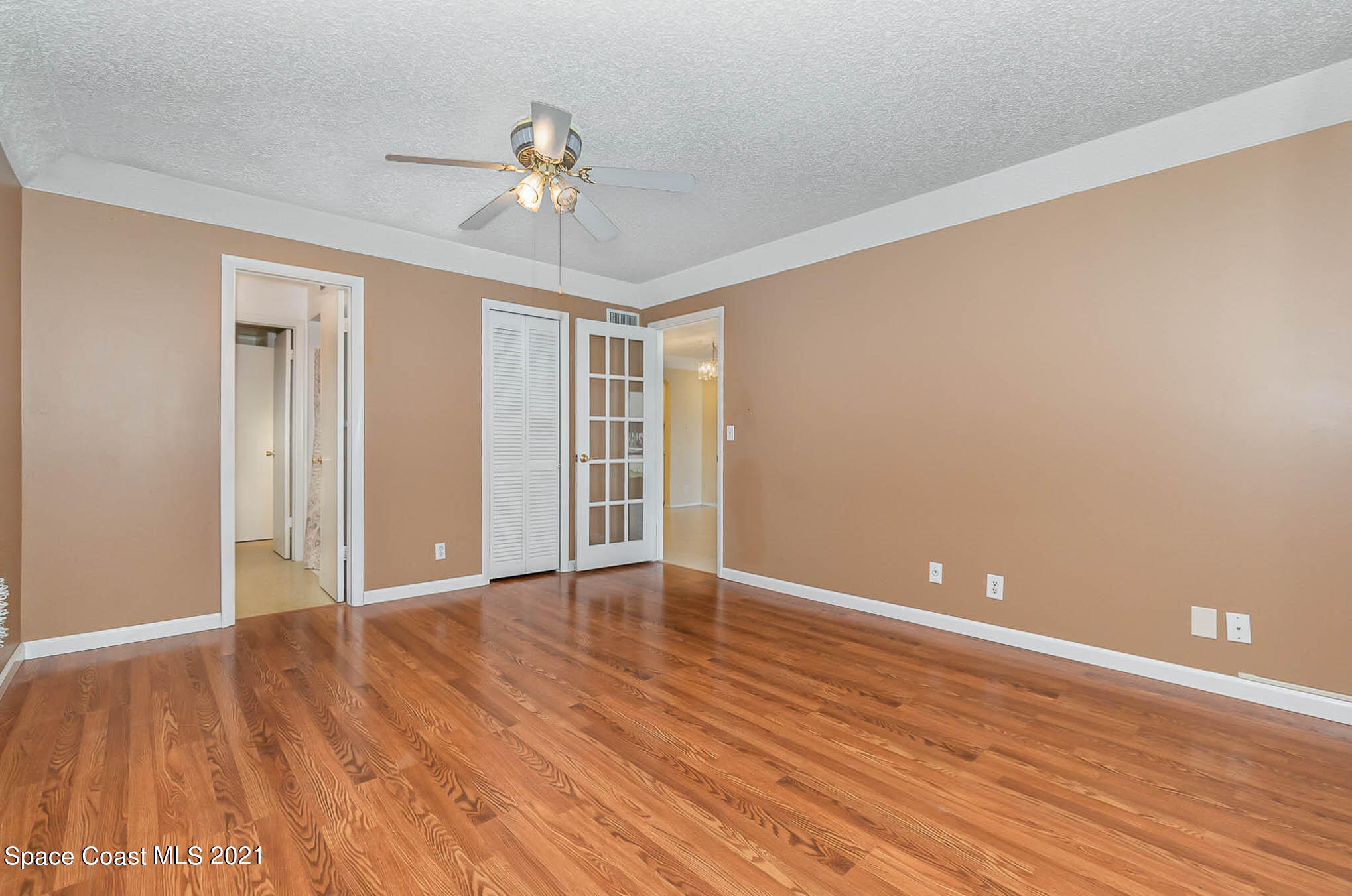 416 School Road, Unit 102 Indian Harbour Beach, FL 32937 - Photo 7 of 27 a view of an empty room with wooden floor and a ceiling fan