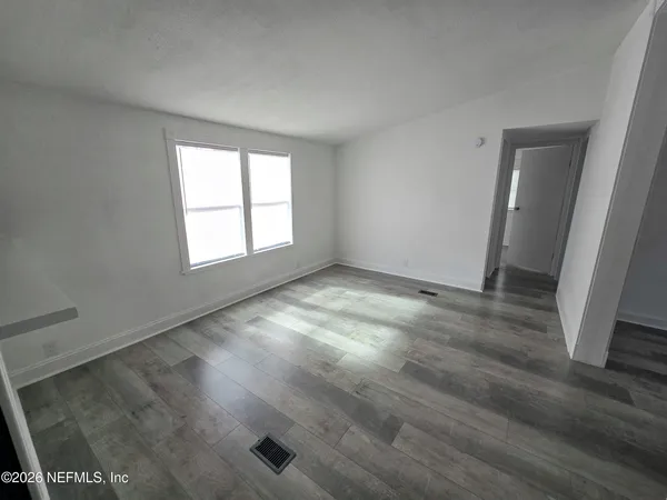 an empty room with wooden floor and windows