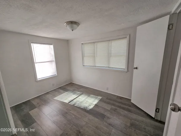 an empty room with wooden floor and windows