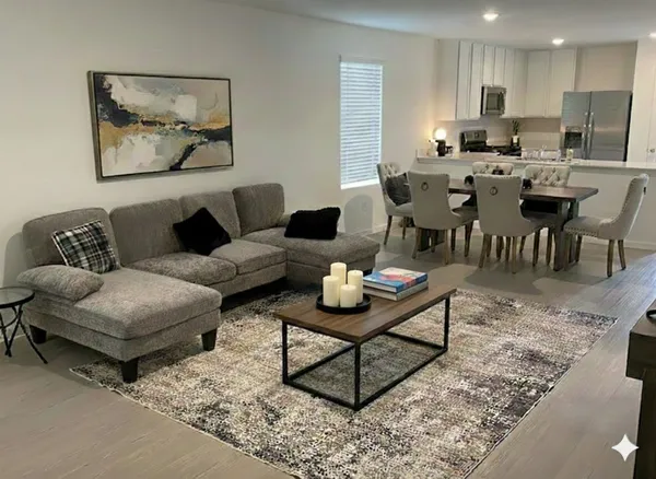 a living room with furniture a rug and kitchen view