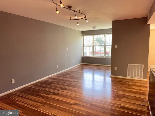 a view of empty room with wooden floor and fan