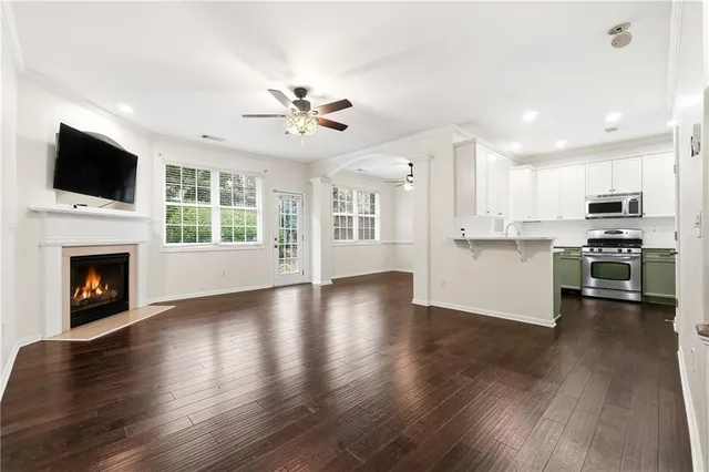 a view of a kitchen with furniture a ceiling fan and wooden floor