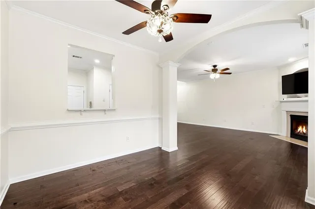 an empty room with wooden floor chandelier fan and windows