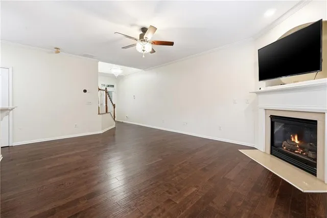 a view of a livingroom with a fireplace a ceiling fan and a kitchen view
