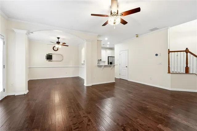 a view of a big room with wooden floor a ceiling fan and a kitchen view