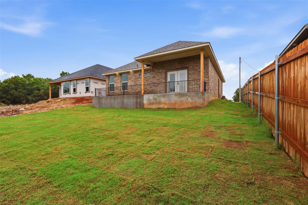 1413 Ridgeview Circle Granbury, TX 76048 - Photo 25 of 35 Brick exterior with a covered patio featuring a black wrought iron railing and double glass doors