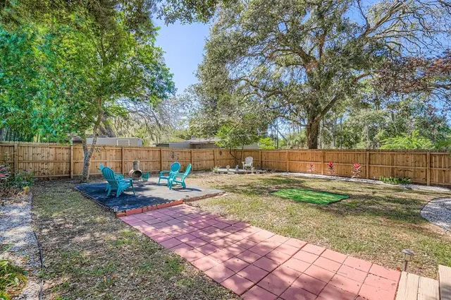 a view of backyard with wooden fence and a large tree