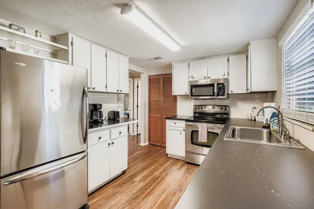 a kitchen with cabinets stainless steel appliances a sink and a counter space
