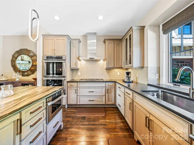 a kitchen with stainless steel appliances granite countertop a stove a sink and a refrigerator
