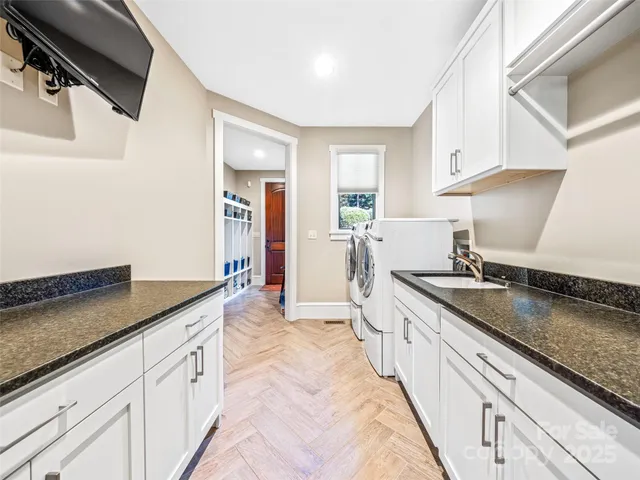 a large kitchen with granite countertop a sink and white cabinets