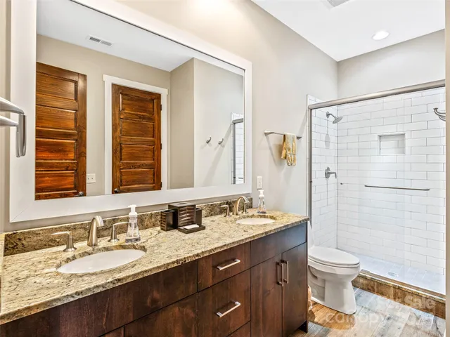 a bathroom with a granite countertop sink toilet a large mirror a shower and a bathtub
