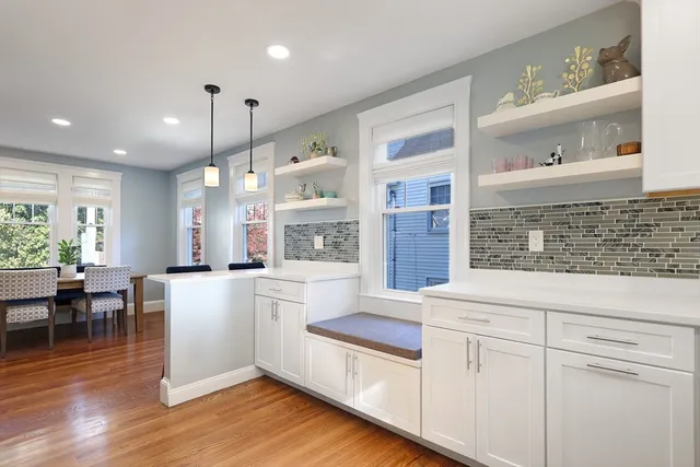 a open kitchen with white cabinets and wooden floor