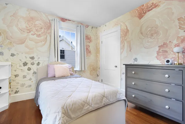 a bedroom with a bed and a potted plant on the dresser