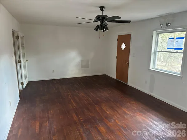 an empty room with wooden floor fan and windows