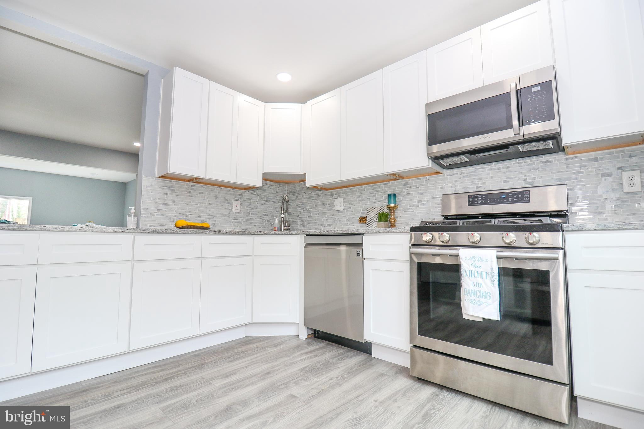 2309 Ravensdon Court Reston, VA 20191 - Photo 16 of 76 a kitchen with stainless steel appliances granite countertop a stove a microwave and a sink