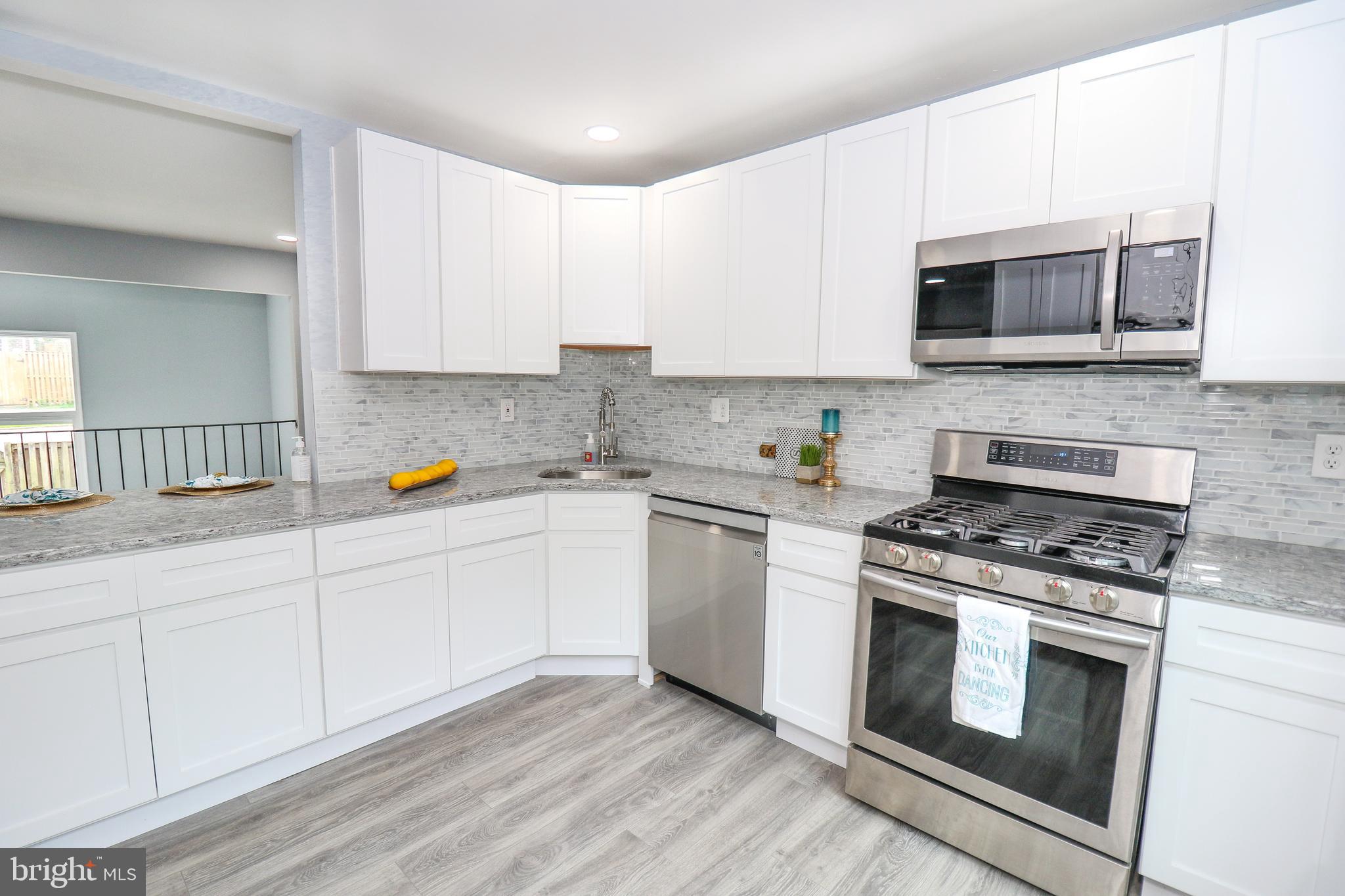 2309 Ravensdon Court Reston, VA 20191 - Photo 7 of 76 a kitchen with stainless steel appliances white cabinets and a stove top oven
