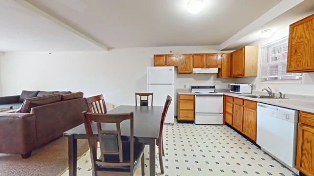 a kitchen with a dining table chairs and a refrigerator