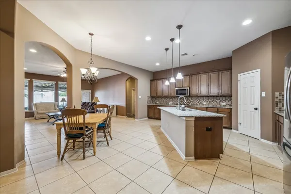 a large kitchen with kitchen island a chandelier dining table and a stainless steel appliances