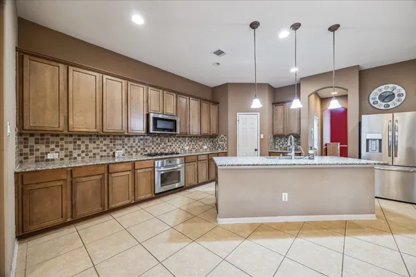 a large kitchen with kitchen island granite countertop a stove a sink a dining table and chairs