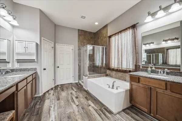a bathroom with a granite countertop tub sink and mirror