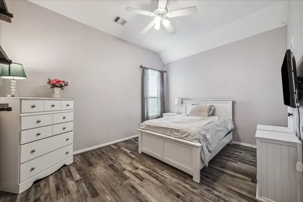 a bedroom with a bed and a flat tv screen on dresser