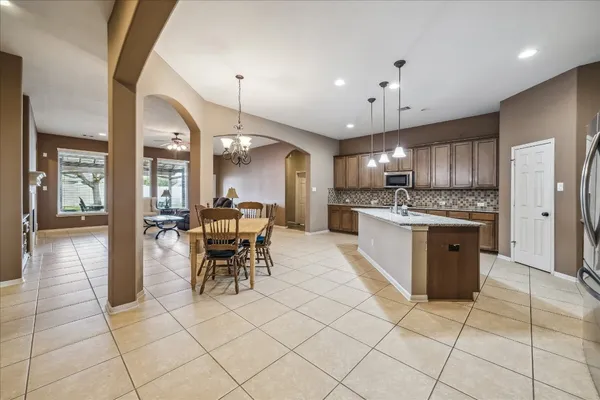 a kitchen with stainless steel appliances granite countertop a stove top oven a sink dishwasher and a refrigerator with wooden floor