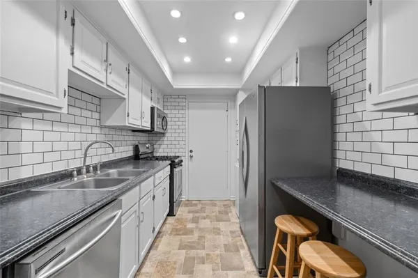 a kitchen with stainless steel appliances granite countertop a sink refrigerator and cabinets