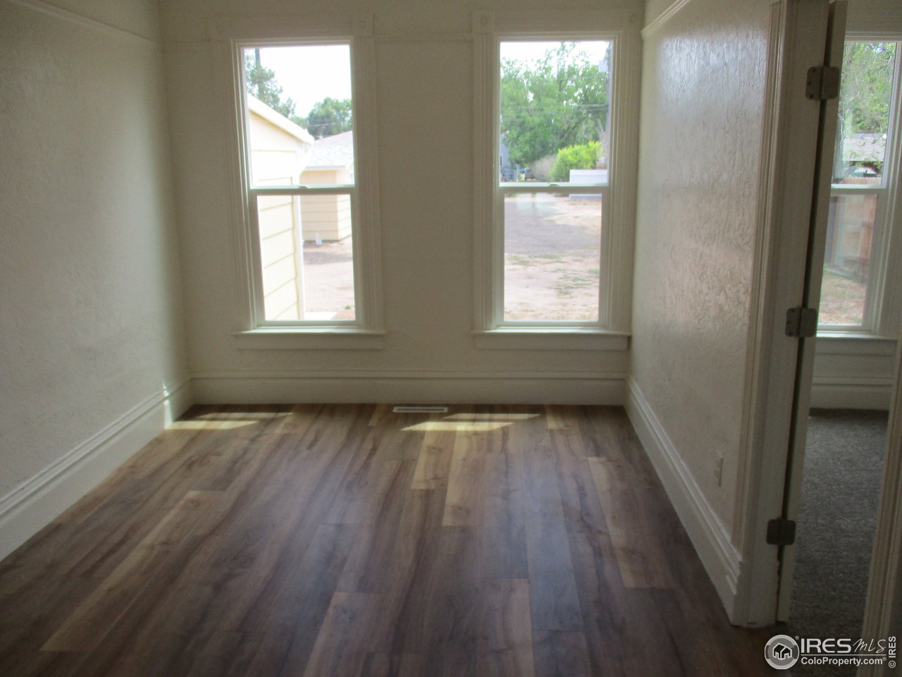 1212 6th Street Greeley, CO 80631 - Photo 4 of 20 a view of an empty room with wooden floor and a window