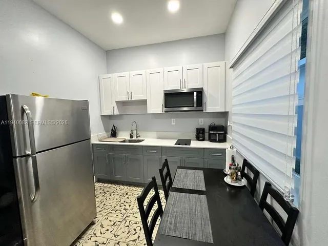 a kitchen with a refrigerator a sink and white cabinets