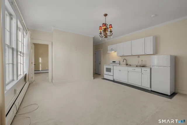 a view of a kitchen with white cabinets and chandelier