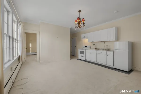 a view of a kitchen with white cabinets and chandelier