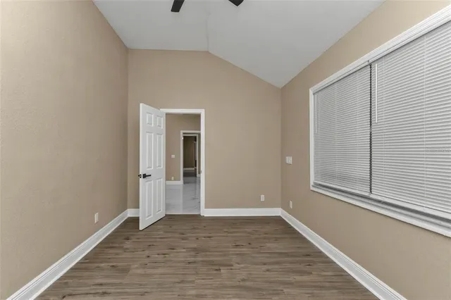 a view of an empty room with wooden floor and a window