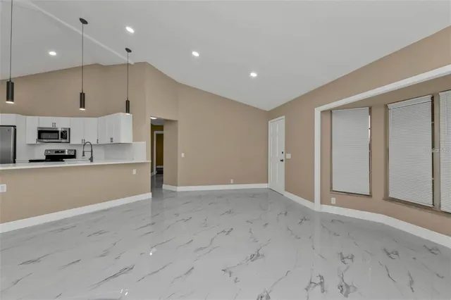 an empty room with kitchen view and a window