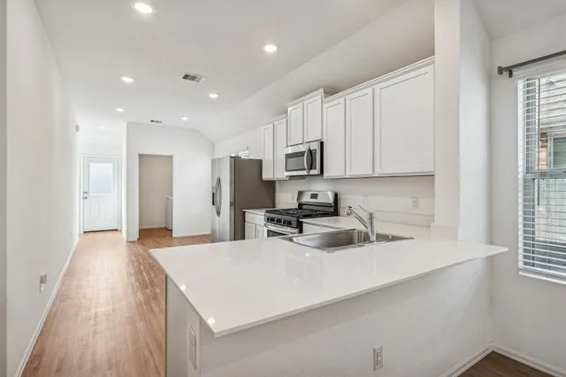 a kitchen with stainless steel appliances a microwave sink refrigerator and cabinets