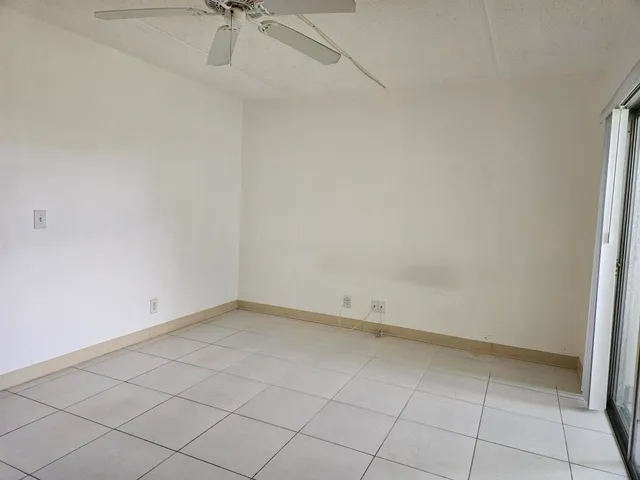 an empty room with a ceiling fan and glass door