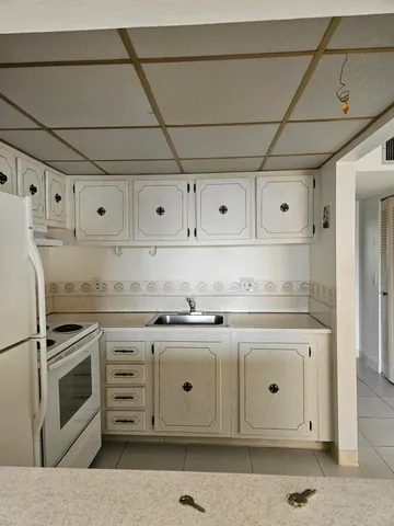 a kitchen with granite countertop white cabinets and white appliances