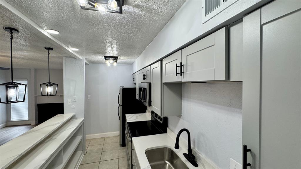 5616 Boca Raton Boulevard, Unit 238 Fort Worth, TX 76112 - Photo 3 of 11 a kitchen with stainless steel appliances kitchen island granite countertop a refrigerator a stove and a sink with granite countertops