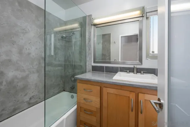 a bathroom with a granite countertop sink a mirror a vanity and shower