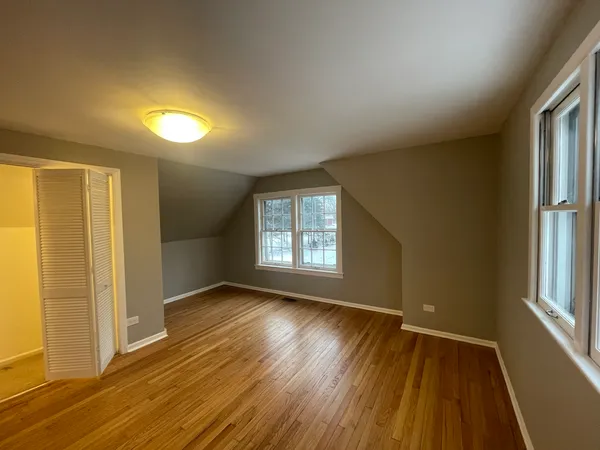 an empty room with wooden floor and windows with curtains