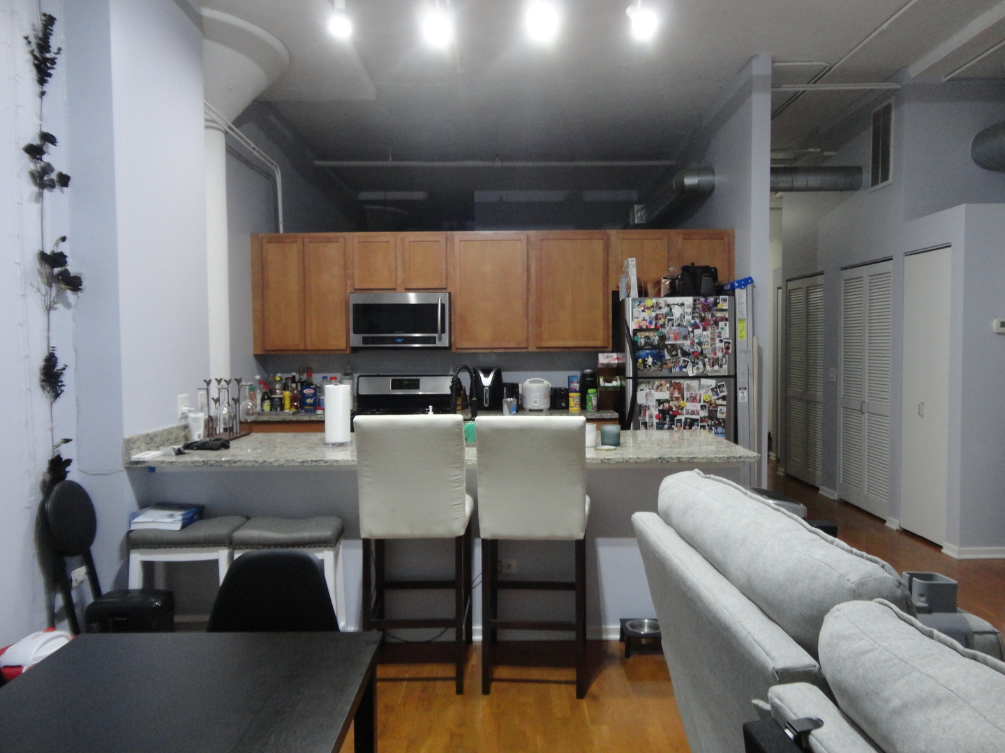 2323 West Pershing Road, Unit 237 Chicago, IL 60609 - Photo 8 of 22 a living room with couches a kitchen view and a stove with wooden floor