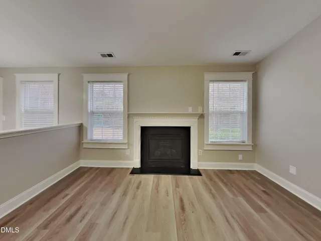 a view of empty room with wooden floor and fireplace