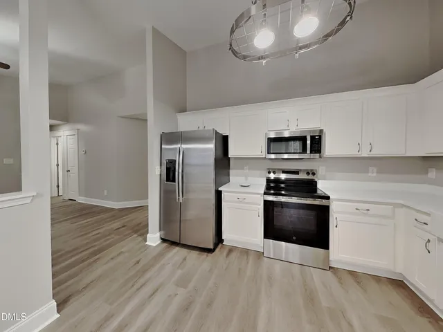 a kitchen with stainless steel appliances granite countertop a refrigerator stove and white cabinets