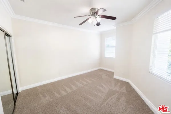 an empty room with windows and fan
