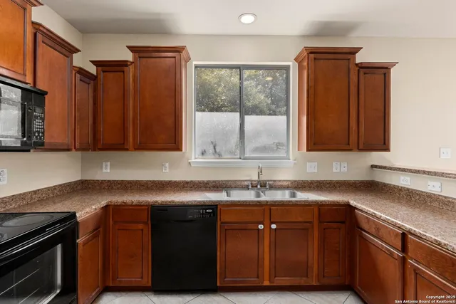 a kitchen with granite countertop stainless steel appliances a sink window and cabinets