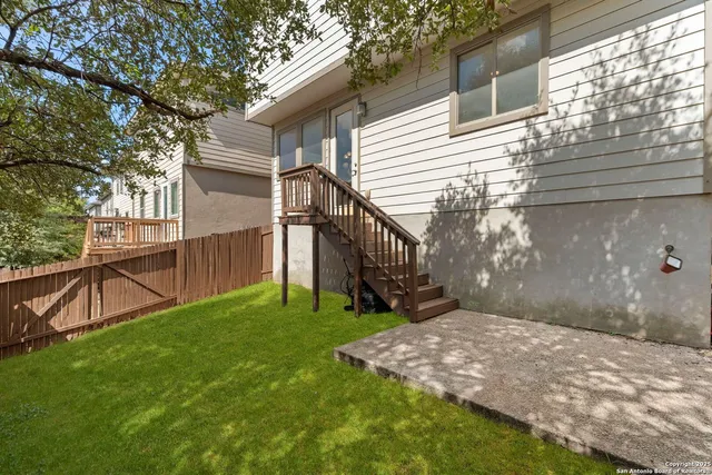 a view of a backyard with wooden fence and a bench