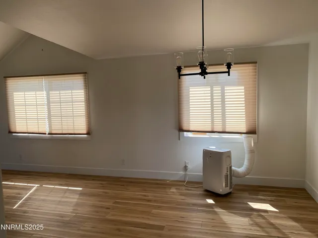a view of empty room with wooden floor and windows