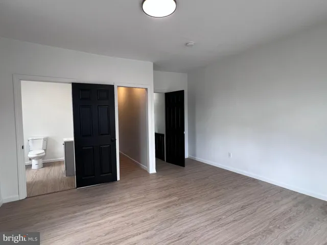 a view of an empty room with wooden floor and a bathroom