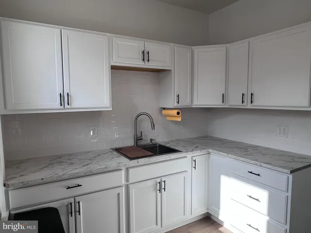 a kitchen with granite countertop white cabinets and a sink