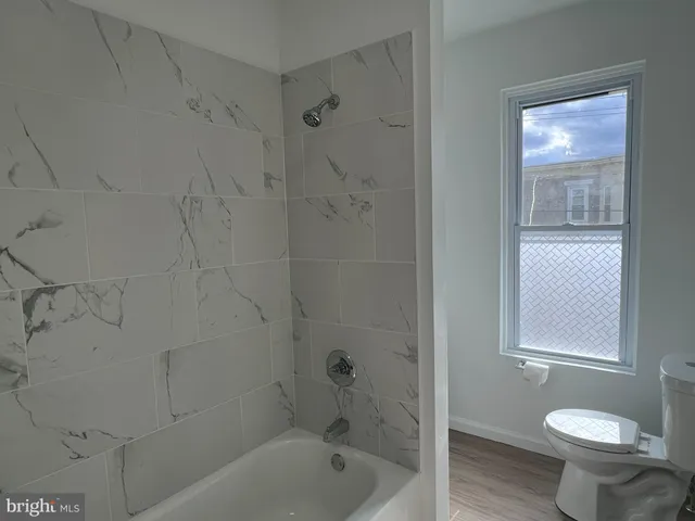 a bath room with a toilet sink shower and a mirror