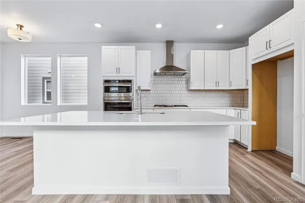 a large kitchen with stainless steel appliances granite countertop a lot of counter space and wooden floors